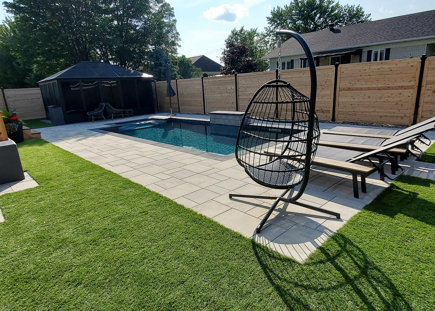 Piscine avec chaises et balancelle.